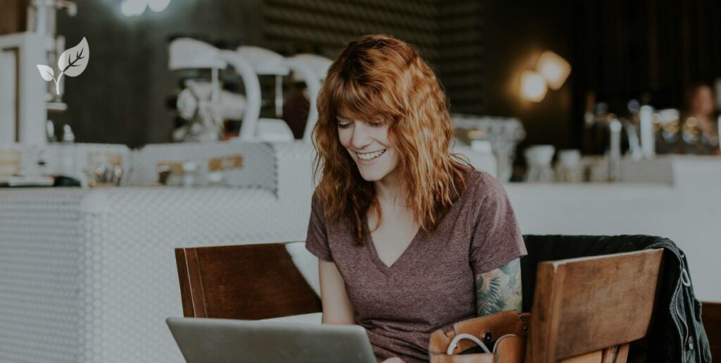 Jeune femme rousse en train de regarder son ordinateur portable