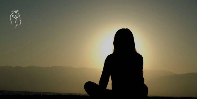 Jeune femme assise face au coucher du soleil