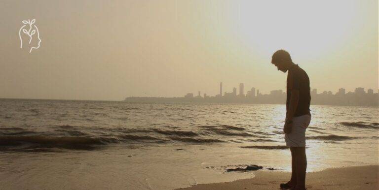 Jeune homme sur la plage au coucher du soleil