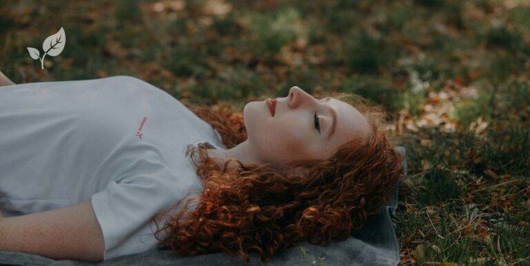 Femme allongée dans l'herbe et qui ferme les yeux