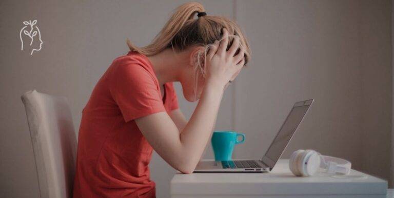 Femme qui se prend la tête dans ses mains devant son ordinateur portable